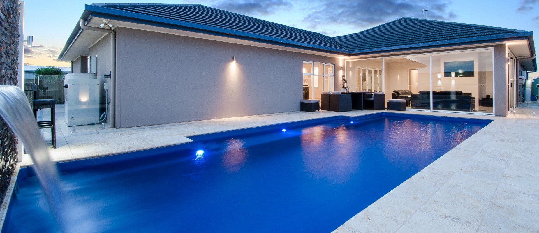 015-Compass-Pools-Australia_Vogue-family-pool-with-water-wall-feature-and-pool-lights-on